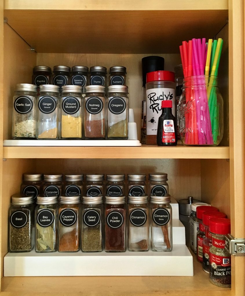 spices with labels lined up in a cupboard, organized pantry